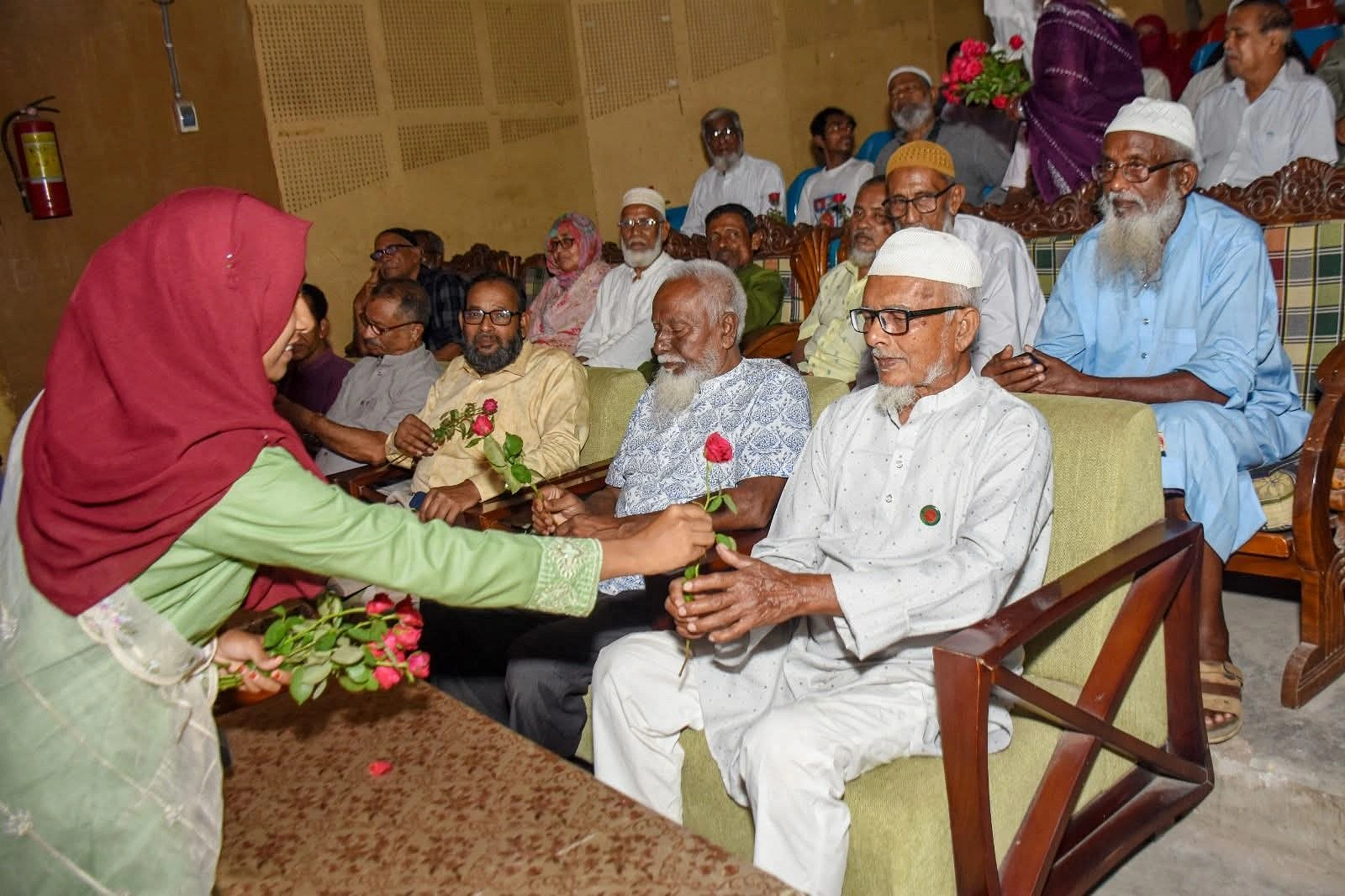 অনুষ্ঠানে অংশ নেওয়া এক প্রবীণ ব্যক্তিকে গোলাপ দিয়ে শুভেচ্ছা জানাচ্ছেন এক তরুণী। ছবি: আগামীর সময়