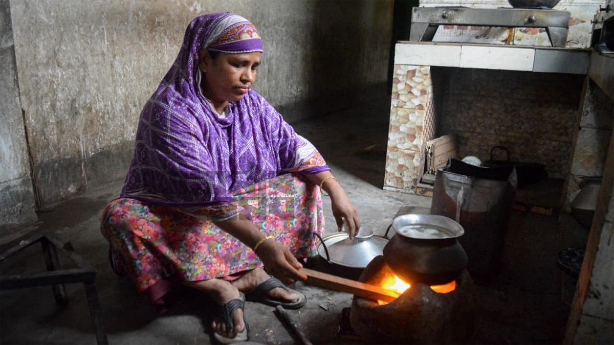 মাটির চুলায় রান্না করছেন এক নারী। ছবি আশিকুর রহমান